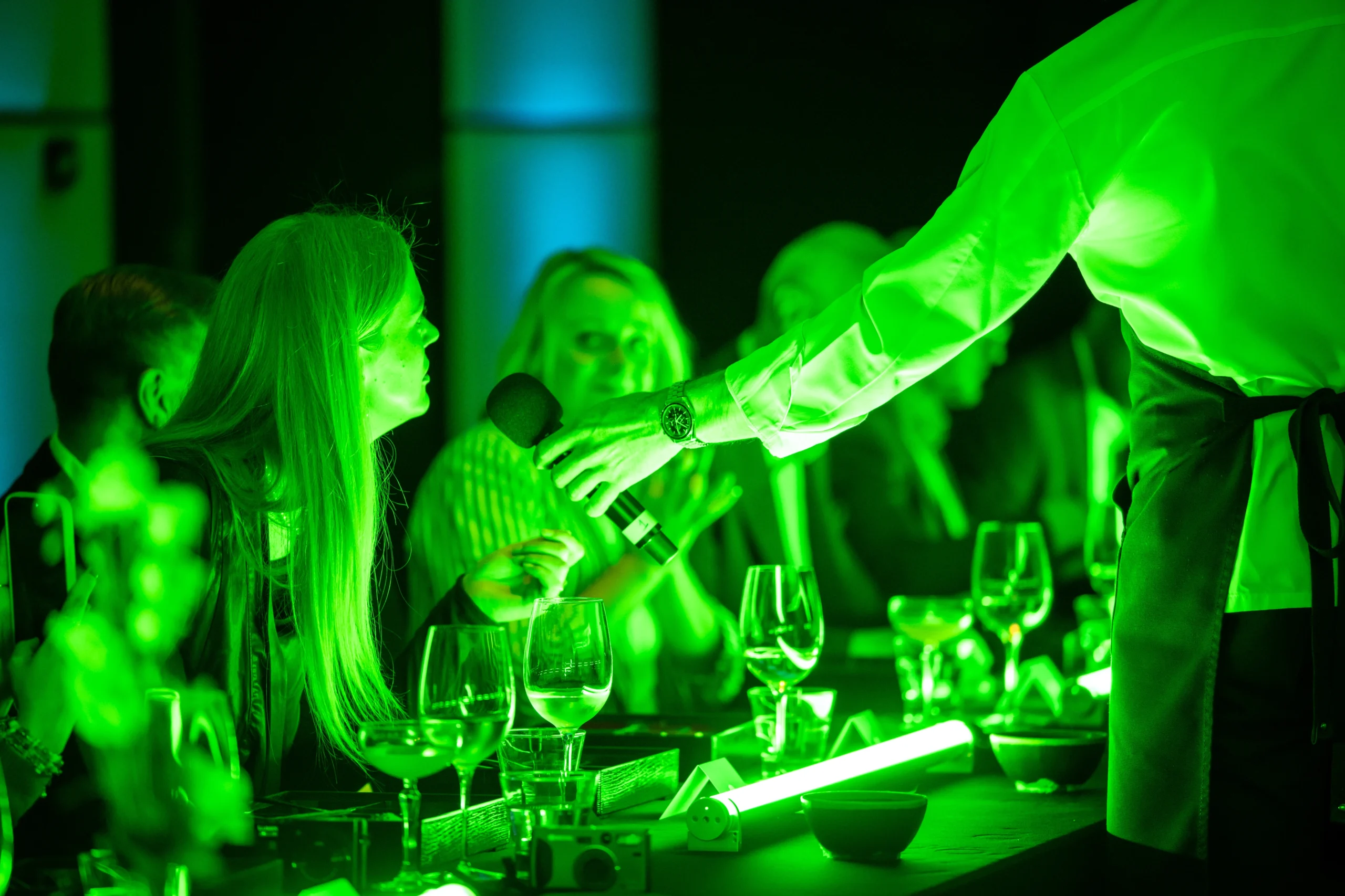 A guest leans into a microphone to ask AI hologram Anna a question during the Pullman London dinner