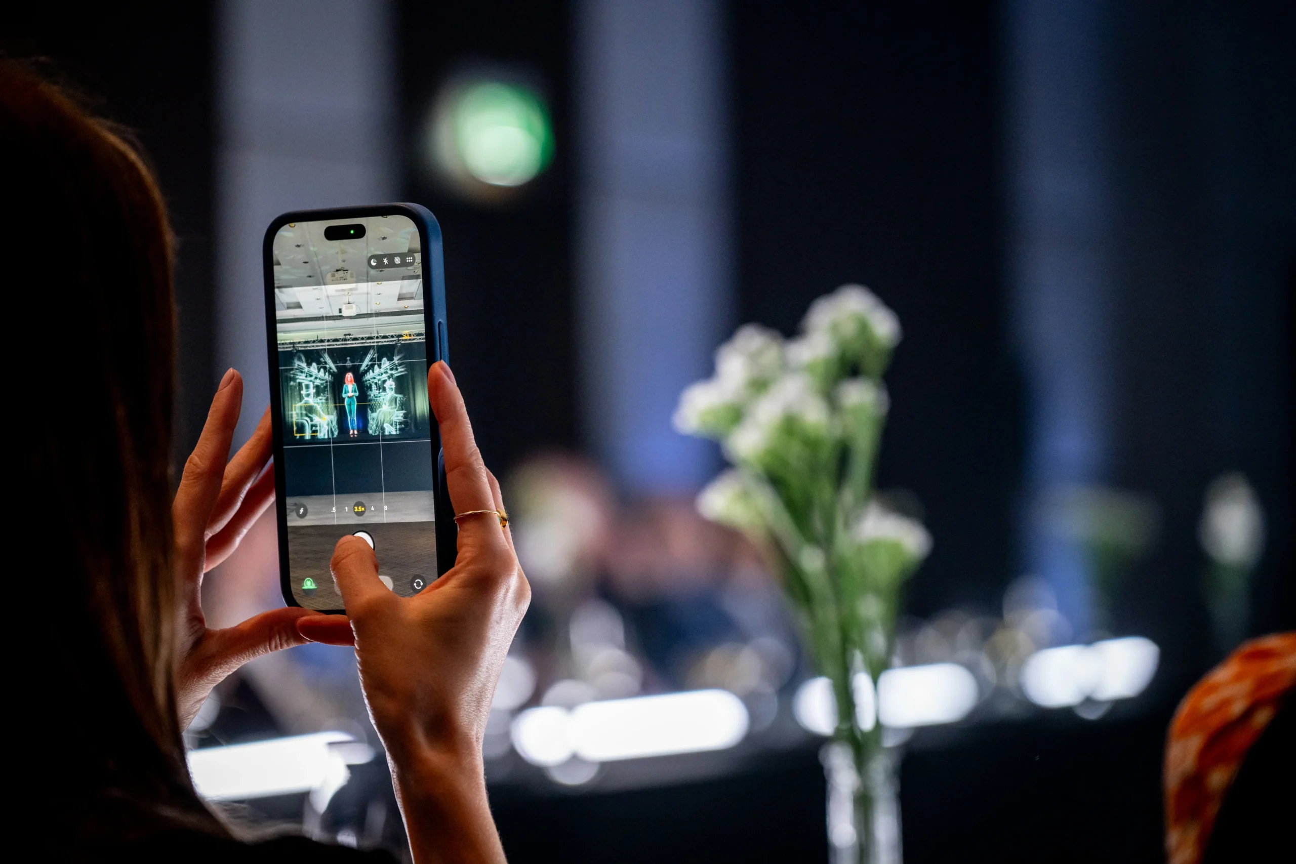 A guest photographs AI hologram Anna on stage through their phone at the Pullman London event